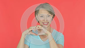 Old Woman showing Heart Shape by Hands on Red Background