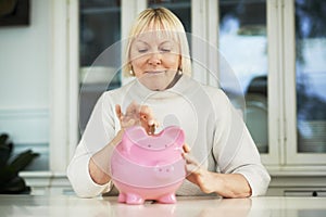 Old woman showing piggybank and euro coin