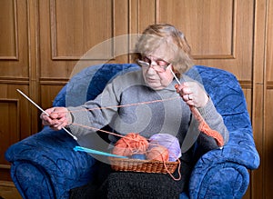 The old woman sits in an armchair
