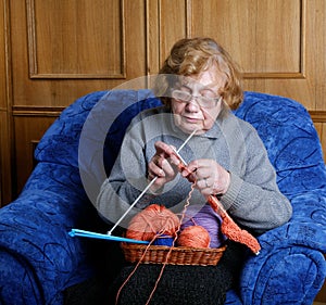 The old woman sits in an armchair