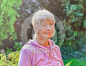 Old woman smiling outside during the sunny day.