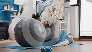 Old woman stretching legs muscles on fitness toning ball