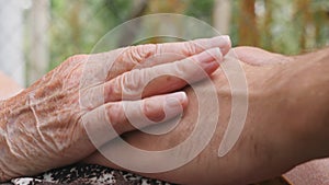 Old woman stroking young male hands outdoor. Grandson and grandmother spending time together outside. Caring and loving