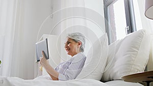 Old woman with tablet pc having video call in bed