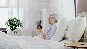 Old woman with tablet pc having video call in bed