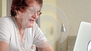 Old woman talk with her granddaughter on skype using a laptop