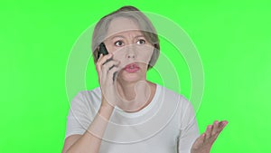 Old Woman Talking Angry on Phone on Green Background