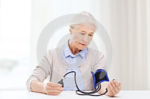 Old woman with tonometer checking blood pressure