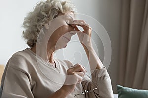 Old woman took off glasses to relief eyestrain feelings photo