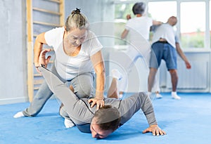 Old woman twisting her opponent& x27;s arm during self-defense classes