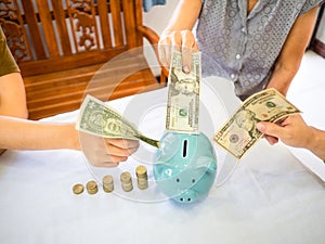 Old woman and two girls hands are putting bank note into blue piggy bank with golden coins graph, Saving money for future plan and