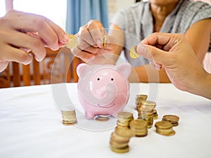 Old woman and two girls hands are putting golden cions into pink piggy bank, Saving money for future plan and retirement fund