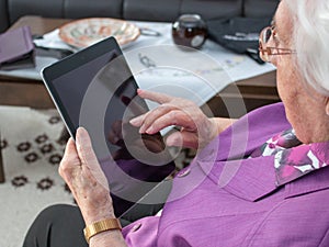 Old woman is typing on a tablet