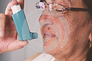 Old woman using asthma inhaler. Asthma Treatment