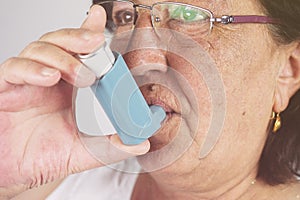 Old woman using asthma inhaler. Asthma Treatment