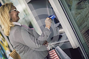 Old woman using ATM machine with credit card