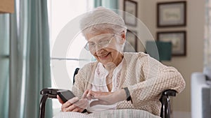 Old woman using smartphone on wheelchair and smile