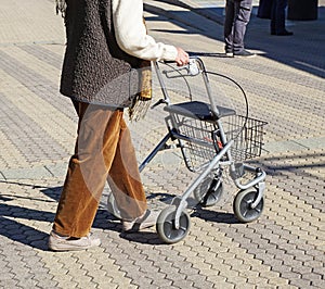 Old woman walks with a wheeled shopping cart