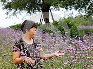 Old woman watch and touch verbena flower, srgb image.