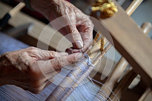 An old woman is weaving