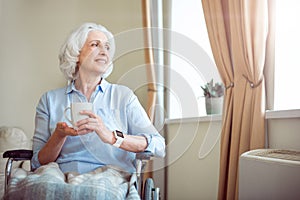 Old woman in wheelchair holding cup