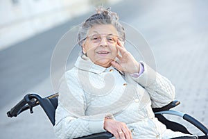 Old woman in wheelchair outdoors smiling