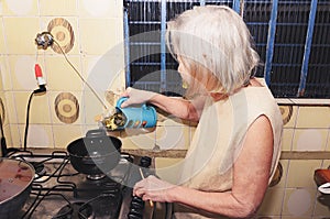 Old woman with white hair cooking at the kitchen photo