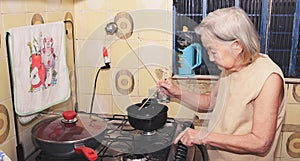 Old woman with white hair at kitchen using a hashi photo