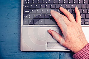 Old woman working on laptop computer at home