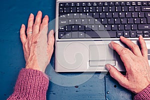 Old woman working on laptop computer at home