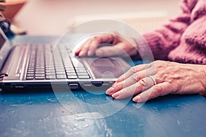 Old woman working on laptop computer at home