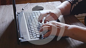 Old woman working on laptop computer at home