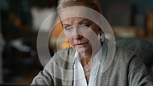 Old woman working laptop computer at home. Elderly lady looking laptop