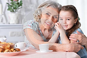 Old woman with a young girl drinking tea