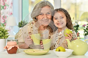 Old woman with a young girl drinking tea on the table