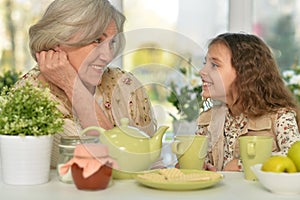 Old woman with a young girl drinking tea on the table