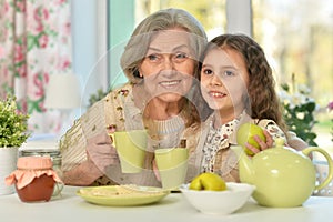 Old woman with a young girl drinking tea on the table