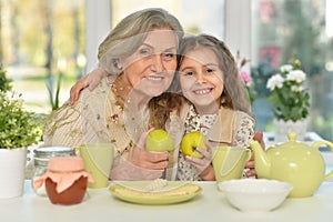 Old woman with a young girl drinking tea on the table