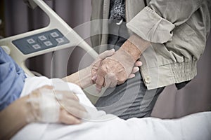 An old women Sick patient lying on bed holding her husband hand in hospital for medical background.Healthcare and Medical for