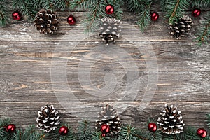 Old wood background with fir branches adorned with baubles and cones. Space for text. Christmas card. Top view