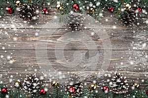 Old wood background with fir branches adorned with baubles and cones. Space for text. Christmas card. Top view. Xmas. Snow effect