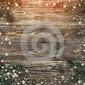 Old wood background with fir branches. Space for a greeting message. Christmas card. Top view. Effect of light and snowflakes