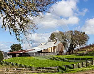 An old wood barn is sitting a field of green grass