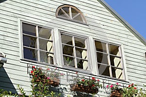 Old wood countryside house with lovely flowers near windows.