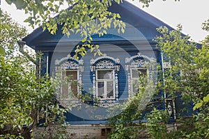 Old wood house in rural landscape with bush and green leafs in summer