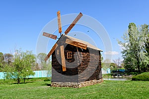Old wood mill and green grass on a small island on the lake from the Chindiei Park (Parcul Chindiei) in Targoviste,