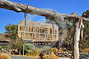 old wood signboard with text welcome to Bakersfield. hanging on a branch