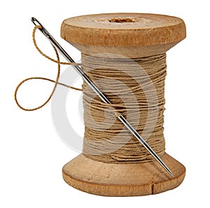 Old wood spool of thread and needle on a white background. Sewing accessories