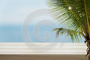 Old wood table top on blurred beach background with coconut leaf