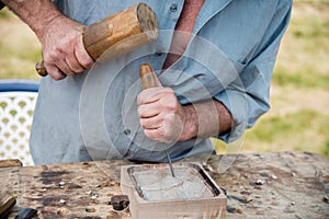 Old woodcarver working with mallet and chiesel